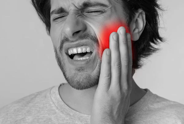 man feeling jaw pain in the tmj area