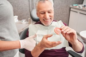 older man holding a denture